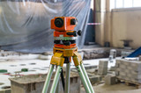 Construction level on a tripod, measuring equipment on a construction site.