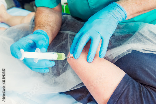 Close up Neurologist doctor makes an injection therapy (blockade) into elbow joint muscle of male patient. Alternative pain treatment concept. Selective focus, space for text.