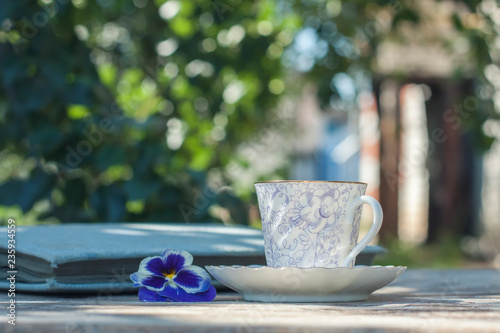 Porcelain cup of tea on a wooden table in the garden. Summer party
