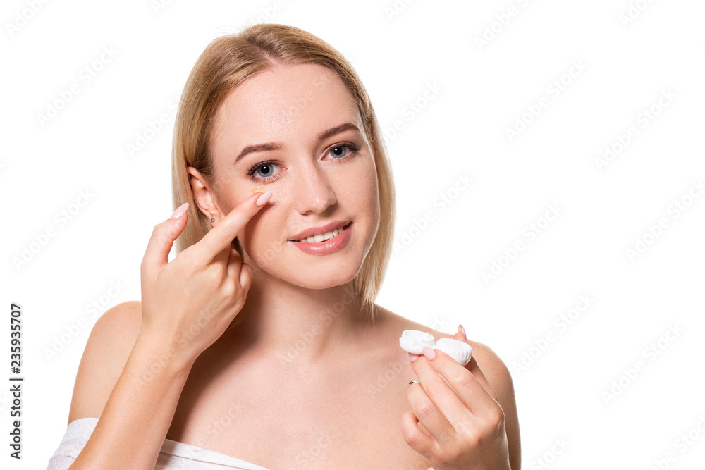 Young woman holding contact lenses cases and lens in front of her face on white background Young woman holding contact lenses cases and lens in front of her face on white background