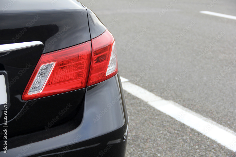Part of a black car on the background of asphalt. Luxury Headlights