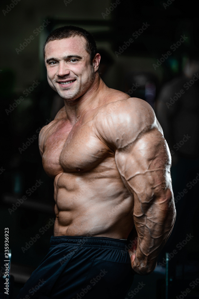 Fototapeta premium Brutal strong bodybuilder athletic muscular men pumping up muscles with dumbbells