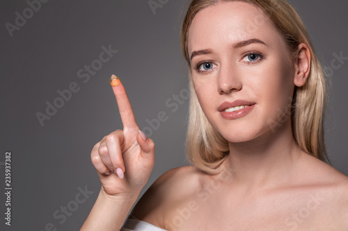 Young woman holding contact lens on index finger with copy space. Close up face of healthy beautiful woman about to wear contact lens.