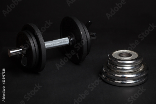 Dumbbell and barbell discs for workout on black background