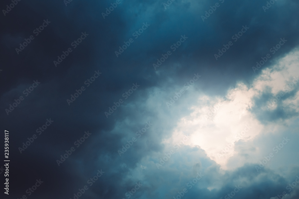 Sun shining through dark blue dramatic clouds in sky. Copy space. For background, wallpaper Sun shining through dark blue dramatic clouds in sky. Copy space. For background, wallpaper