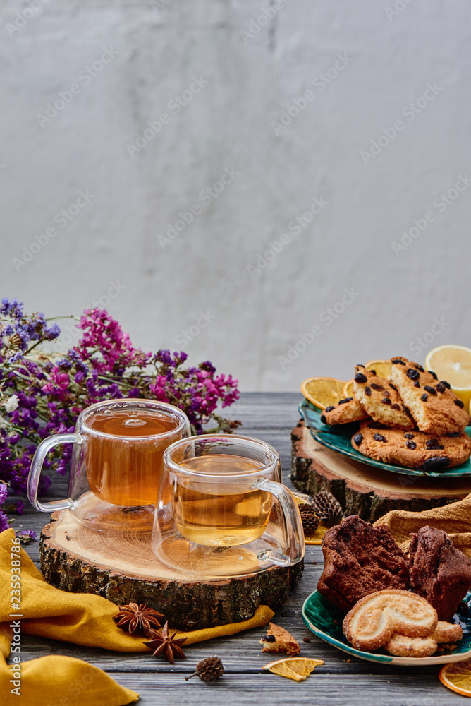 two glass cups of tea on a wooden saw, with cookies and dried flowers on the background. wooden background. autumn tea composition. close-up