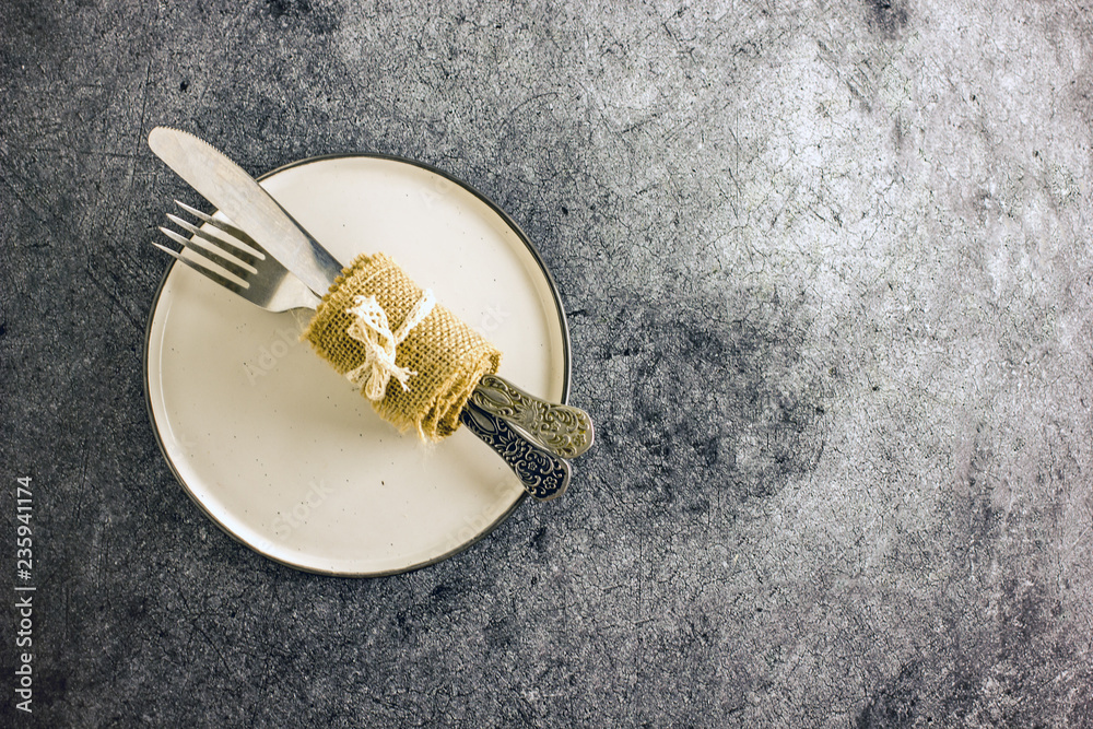 White plate and cutlery on stone table top view. Table setting. White plate and cutlery on stone table top view. Table setting.