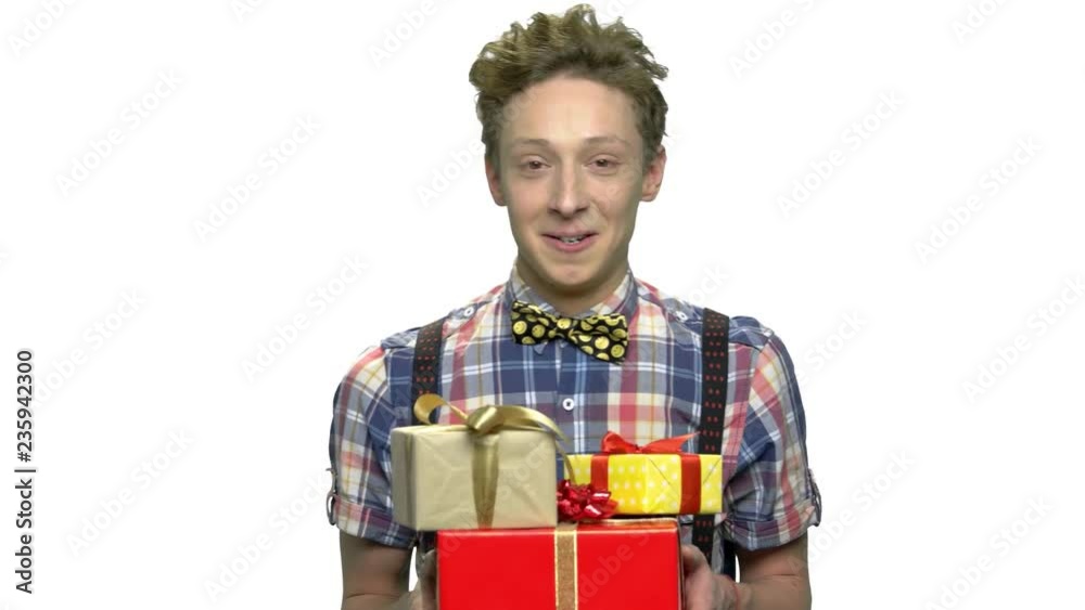 Portrait of funny boy with gift boxes. Expressive teen guy with stack of gifts looking at camera. Birthday surprise concept. Portrait of funny boy with gift boxes. Expressive teen guy with stack of gifts looking at camera. Birthday surprise concept.