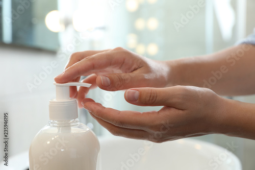 Woman applying liquid soap on hand in bathroom, closeup