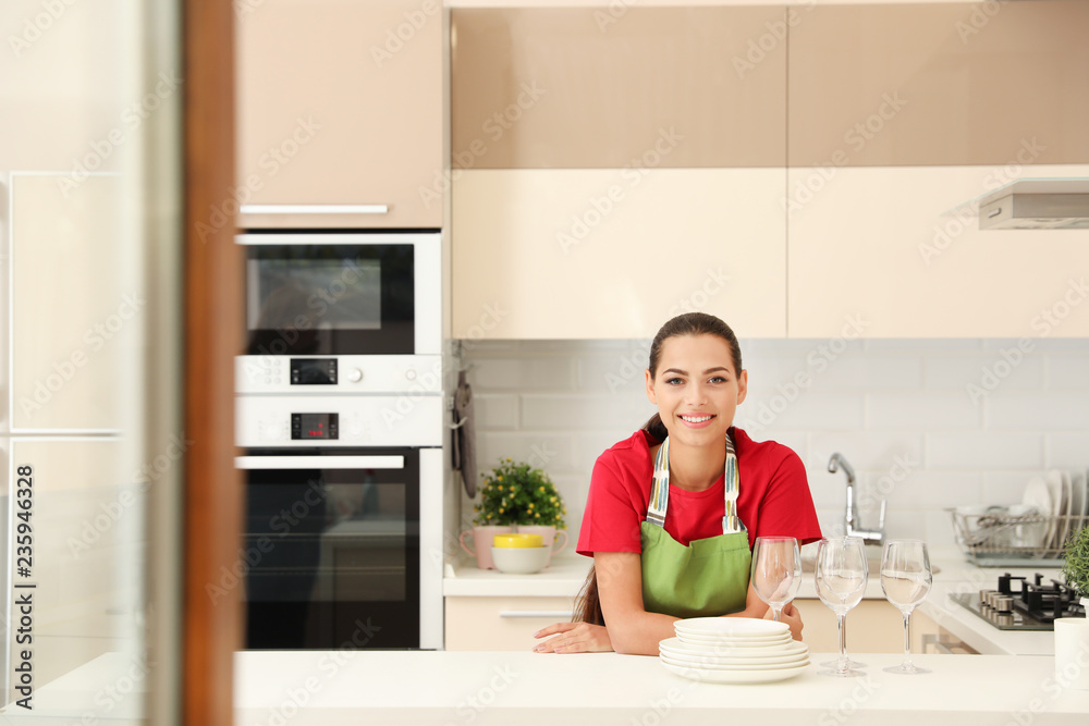 Beautiful young woman with clean dishes in kitchen Beautiful young woman with clean dishes in kitchen