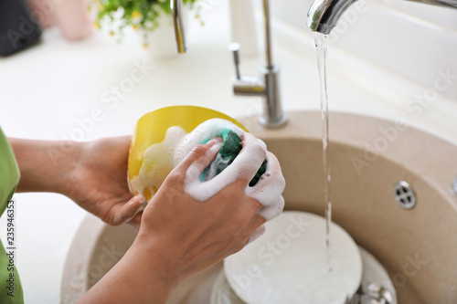 Woman washing dirty dishes in kitchen sink, closeup. Cleaning chores