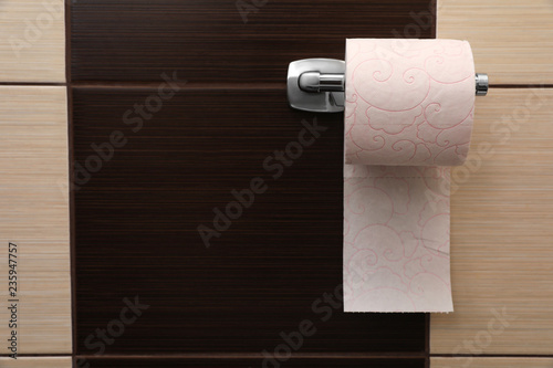 Holder with soft toilet paper roll in bathroom. Space for text