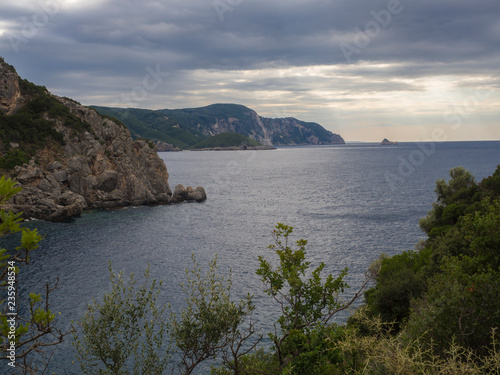 View on cllifs, trees and green hill at Paleokastritsa bay, summer cloudy sky, Corfu, Kerkyra, Greece photo