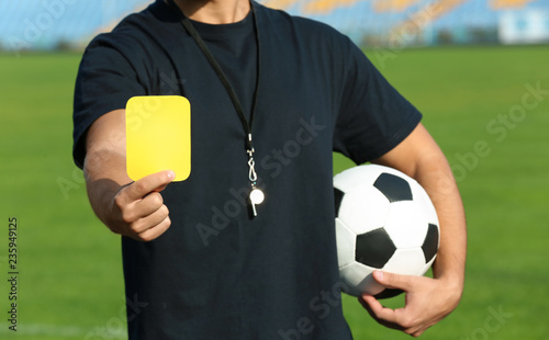 Football referee showing yellow card at stadium, closeup