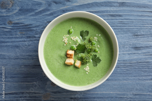Fresh vegetable detox soup made of green peas and broccoli in dish on wooden background, top view