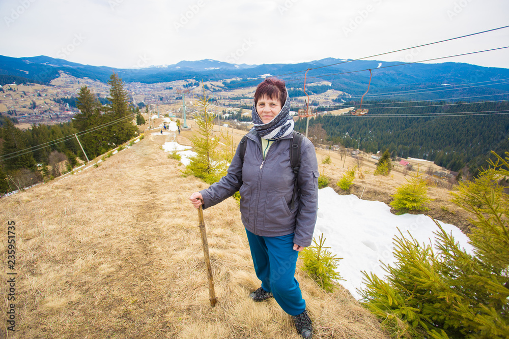 Elderly woman 60 years old hiking in mountains with snow admiring beautiful view
