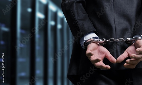 Cropped image of male hands in handcuffs behind his back photo
