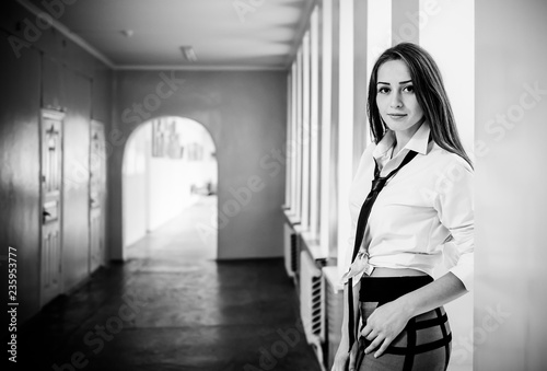 young brutet woman standing in corridor of high school near window lights