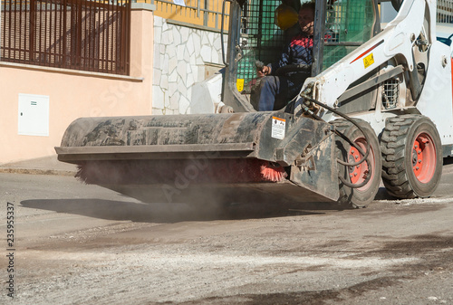 Sweeper attachments mini excavator. The sweeper sweeps  collects and dumps dirt and debris.