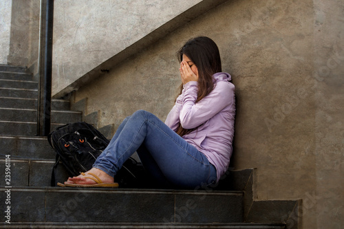 depressed student woman or bullied teenager girl sitting outdoors on street staircase scared and anxious victim of bullying feeling desperate suffering depression photo