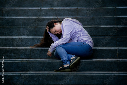 depressed Asian Chinese student woman or bullied teenager sitting outdoors on street staircase overwhelmed and anxious feeling desperate suffering depression