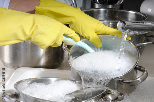 WASHING POTS AND PANS WEARING RUBBER GLOVES