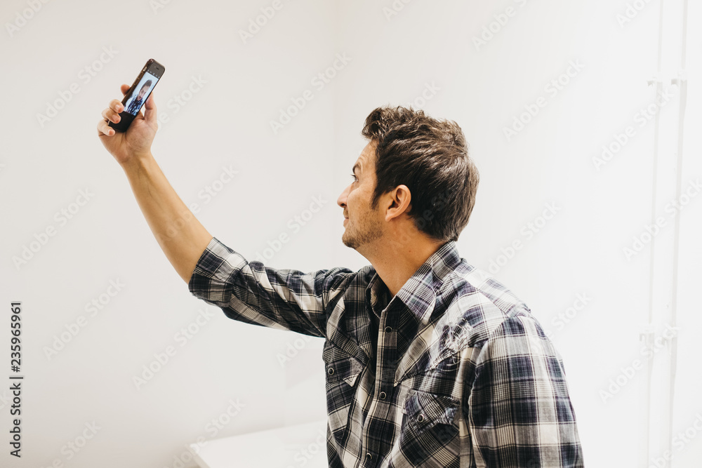 Smiling young man taking selfie on smartphone
