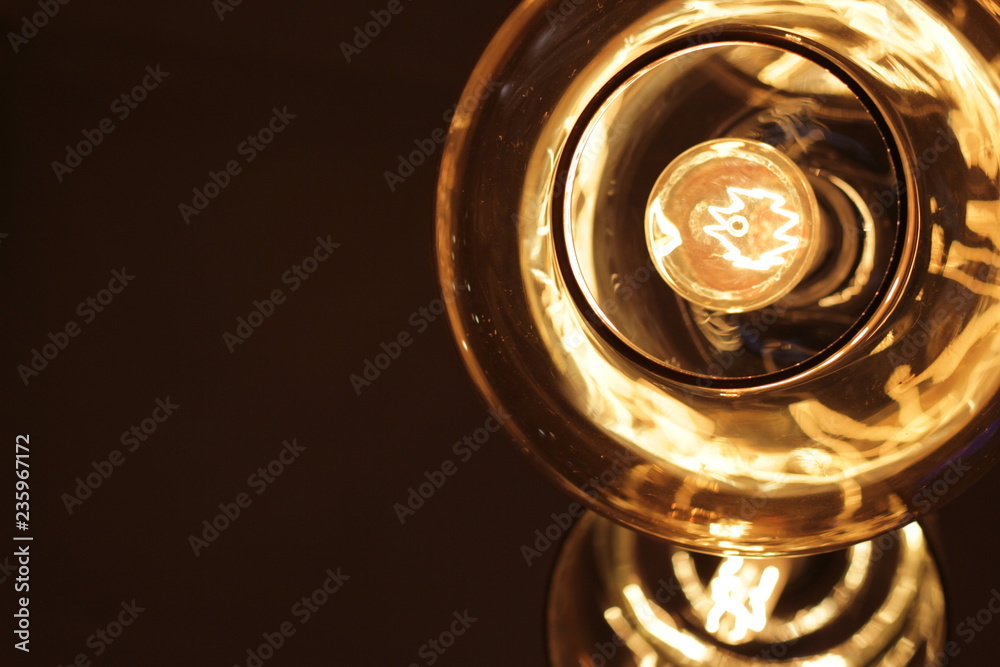 Glass ceiling and Edison light bulb on dark background with space for text. Close-up. Glass ceiling and Edison light bulb on dark background with space for text. Close-up.