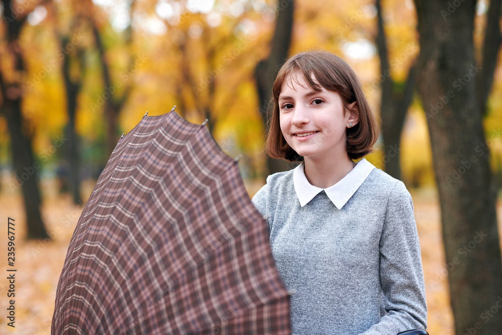 Teen girl with umbrella posing in autumn park. Bright yellow leaves and trees. She imitates the wind. Teen girl with umbrella posing in autumn park. Bright yellow leaves and trees. She imitates the wind.