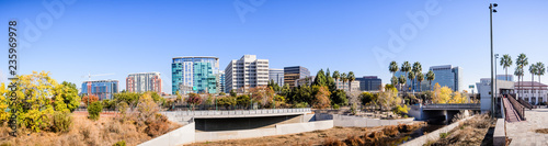 Panoramic view of San Jose's downtown skyline as seen from the shoreline of Guadalupe river on a sunny fall day; Silicon Valley, California