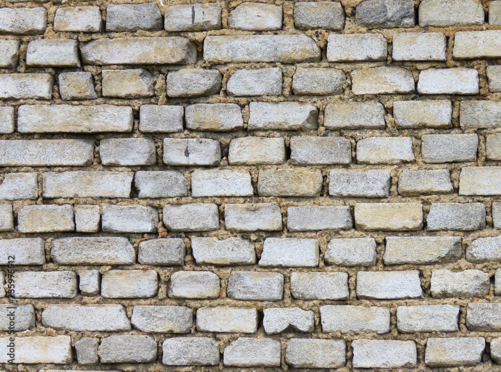 Old brick gray wall, the wall of a house without plaster. Many bricks connected by mortar. Old method of masonry. Construction, background, wallpaper.