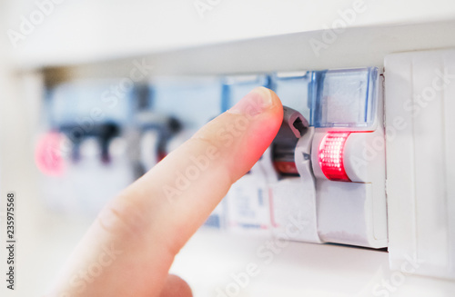 Male hand switching off fuse board. photo