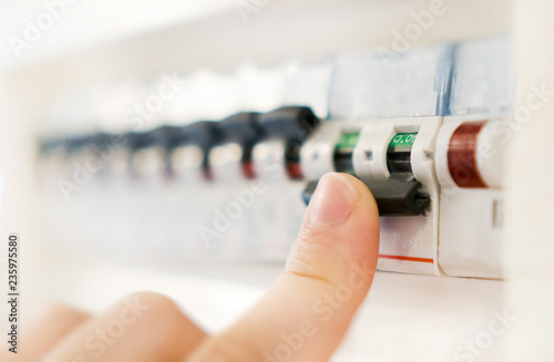 Male hand switching off fuse board. photo