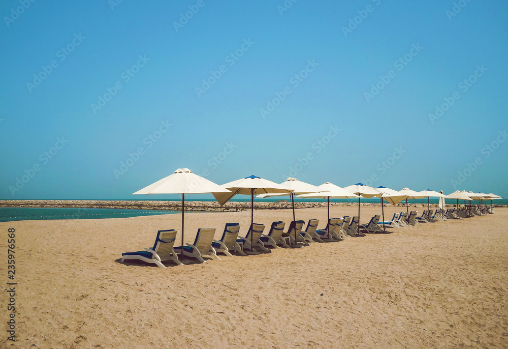 The Shore Of The Arabian Gulf. The Emirate Of Ras Al Khaimah. Beautiful sea minimalism with umbrellas and yellow sand. The Shore Of The Arabian Gulf. The Emirate Of Ras Al Khaimah. Beautiful sea minimalism with umbrellas and yellow sand.