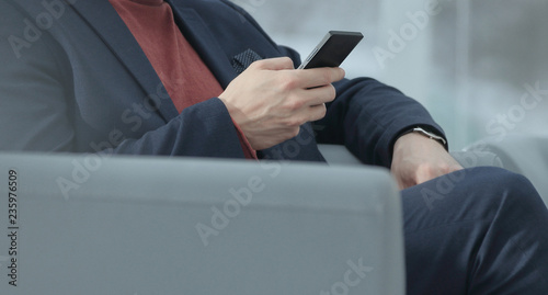 close up.businessman using mobile phone sitting in the lobby