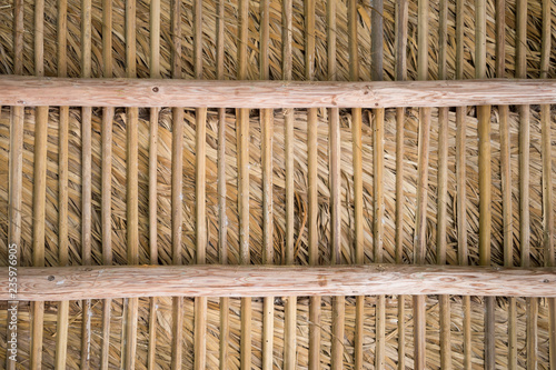 Rustic natural tropical background of weathered wooden slats supporting a layer of dried palm fronds in a full frame abstract close-up photo