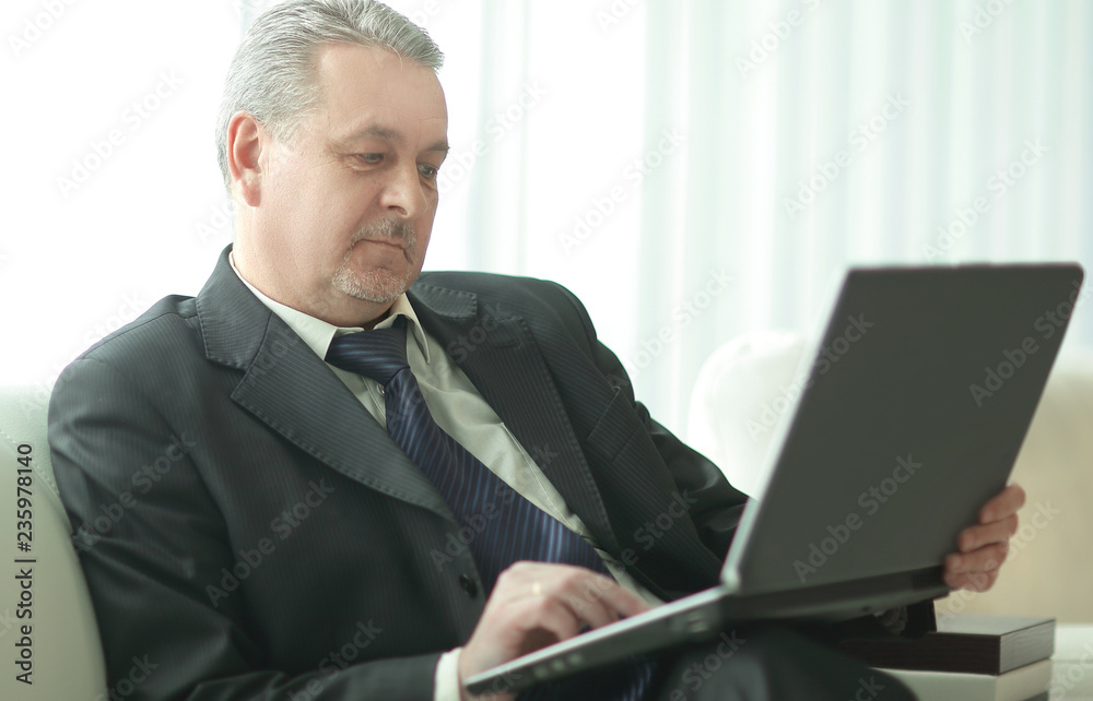 successful businessman using laptop sitting in office lobby successful businessman using laptop sitting in office lobby