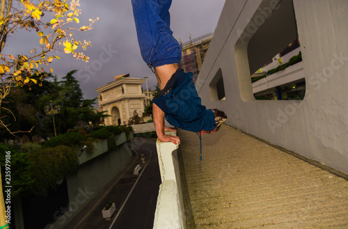 Young parkour man perform handstand at urban place