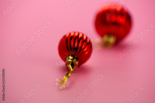 Christmas balls with a golden ribbon on a blurred pink background.