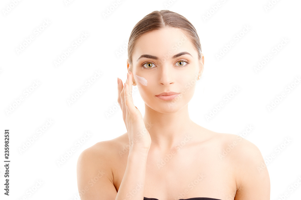 Woman applying cream onto her face against white background, Studio beauty shot