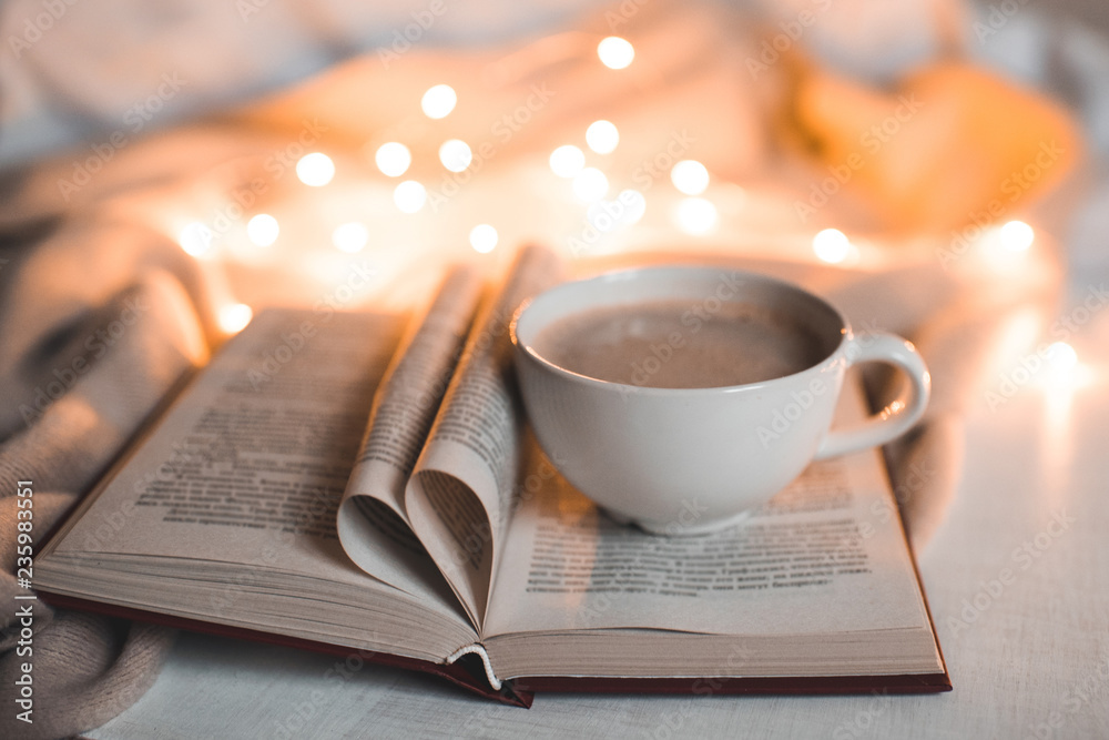 Cup of coffee staying on open book with heart shaped pages over lights at  background. Cozy morning. Bedtime. Stock Photo | Adobe Stock