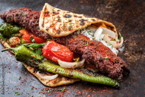 Traditioneller Adana Kebap Grillspieß mit Tomaten und  with tomato and Jogurt als  closeup auf einem Fladenbrot