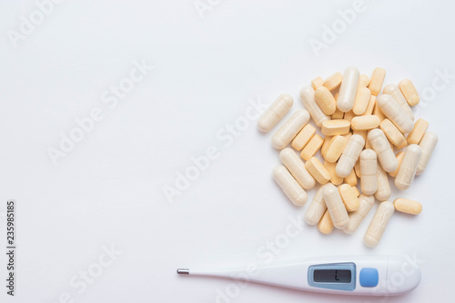 Medical thermometer, pills and capsules with the drug. Top view on white background with place for text. free space. antibiotics from the disease. treatment. photo