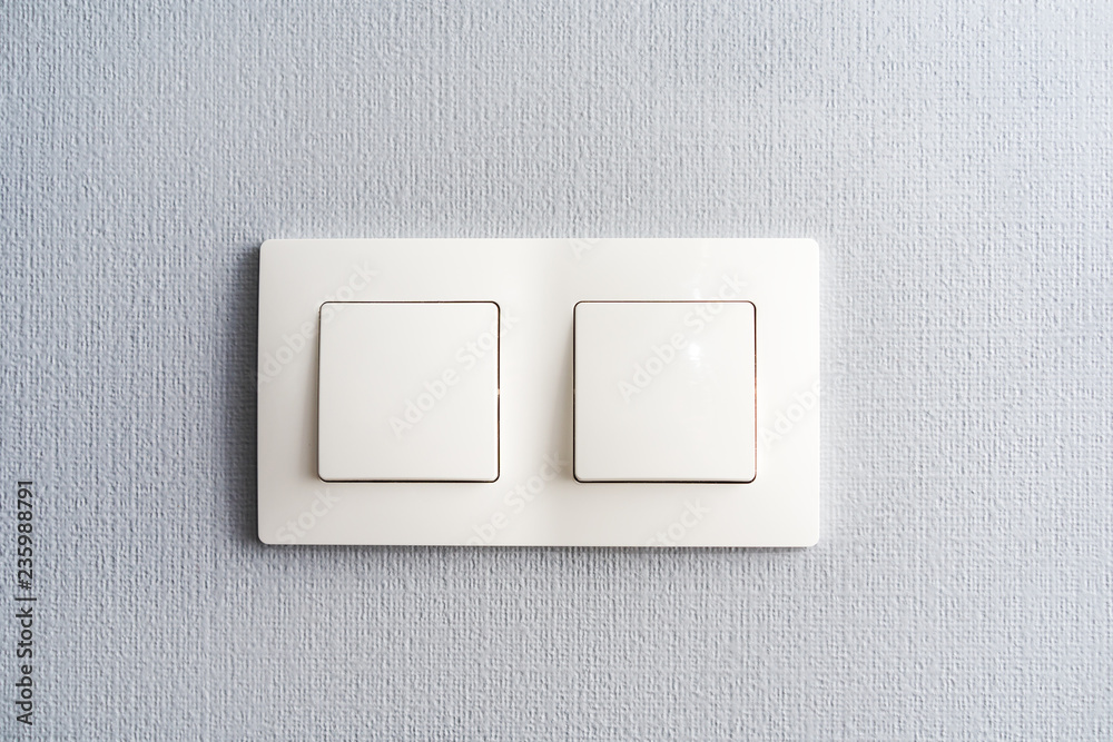 a light switch, a plastic mechanical switch of white color installed on a light gray wall in the room a light switch, a plastic mechanical switch of white color installed on a light gray wall in the room