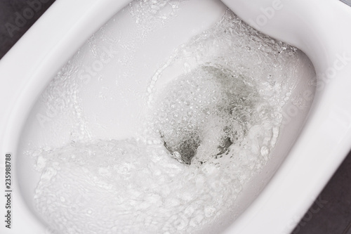 Flush toilet. Water flushes the toilet. The flow of water is clearly visible.