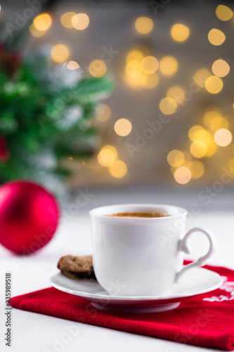 Cup of espresso or americano coffee in white cup in cozy Christmas arrangement  festive decoration with bokeh background  copy space