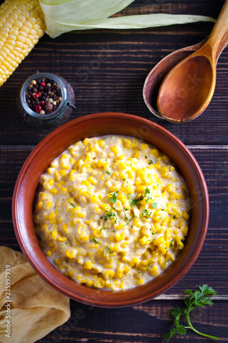 Sweet and creamy corn in bowl. Corn dish. overhead, vertical