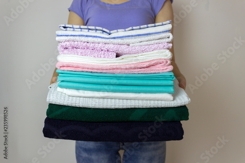 Clean clothes from laundry in a stack in the hands of a housewife
