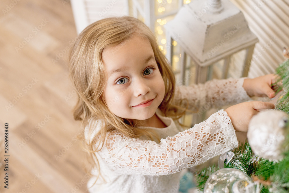 Fototapeta premium happy girl decorates the Christmas tree