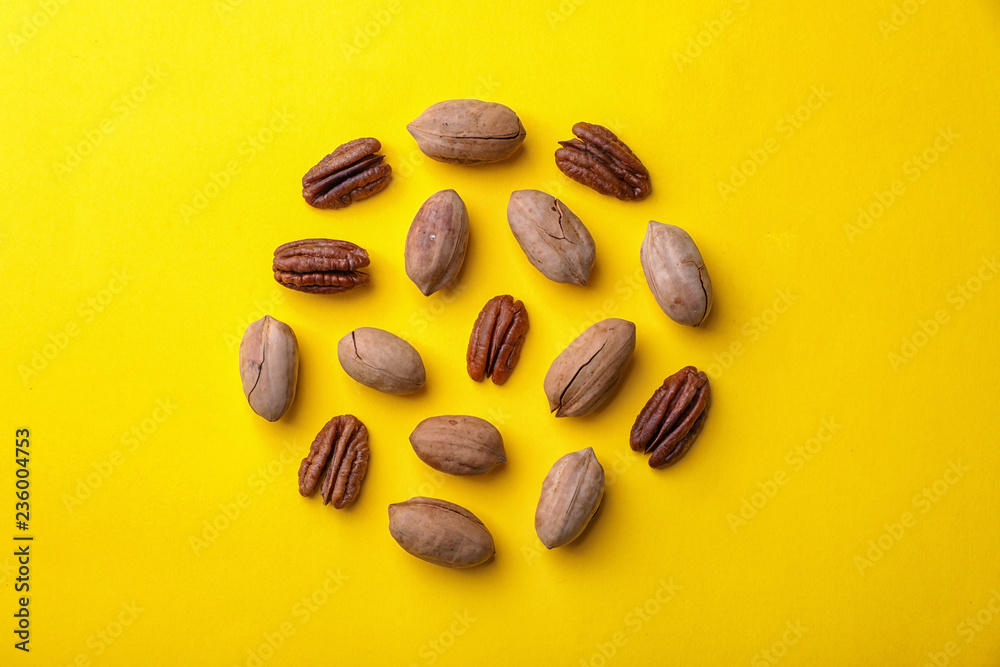 Composition with pecan nuts on color background, top view